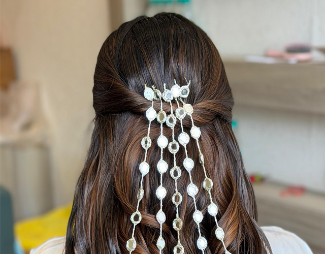 Elegant hairstyling by Nithika Aroraa featuring a half-up hairstyle adorned with pearl hair accessories.